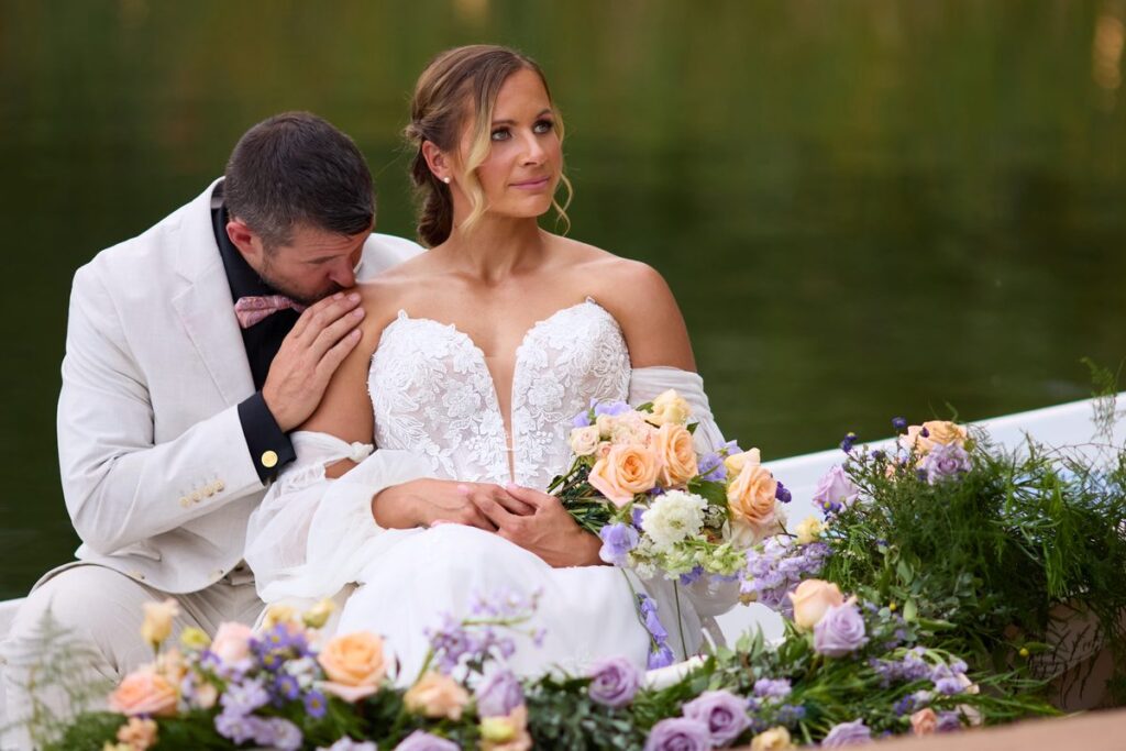 Bride and groom laughing together in a flower rowboat on the pond at Lazy Stud Ranch, Lyons Colorado