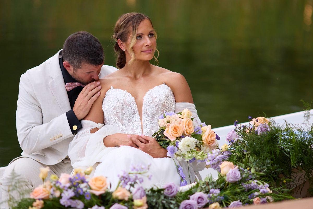 Bride and groom laughing together in a flower rowboat on the pond at Lazy Stud Ranch, Lyons Colorado