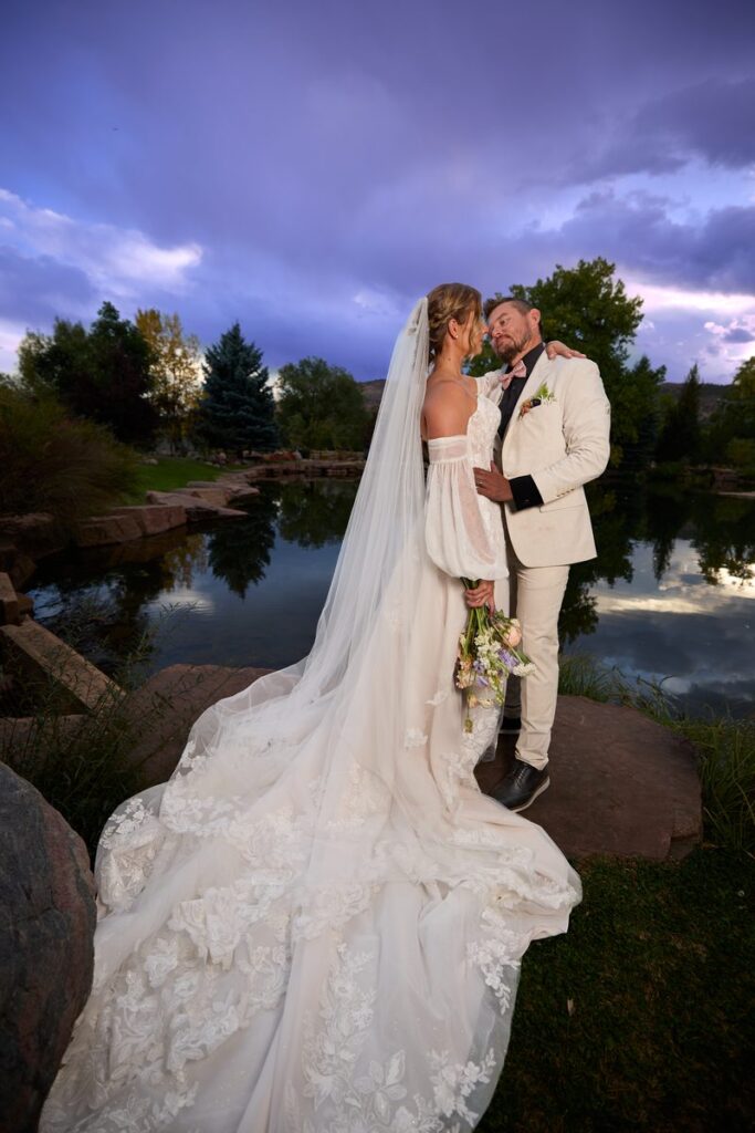 Bride and groom under flowing veil at twilight with purple sky and Colorado mountains, Lazy Stud Ranch Lyons